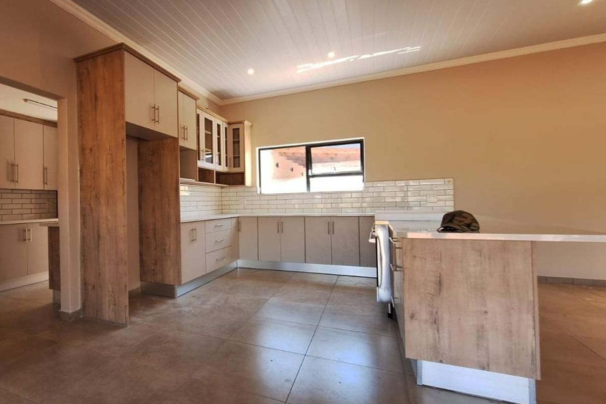 Modern kitchen featuring wood-look cabinetry, a central island, subway tile backsplash, and tiled flooring in an open-plan layout.
