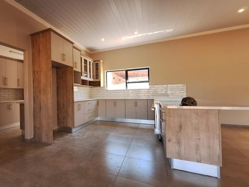 Modern kitchen featuring wood-look cabinetry, a central island, subway tile backsplash, and tiled flooring in an open-plan layout.
