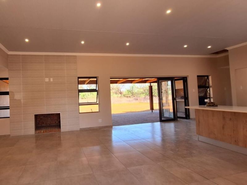 Spacious open-plan living area featuring tiled floors, a built-in fireplace with a tiled feature wall, and bi-fold doors leading to an outdoor patio.