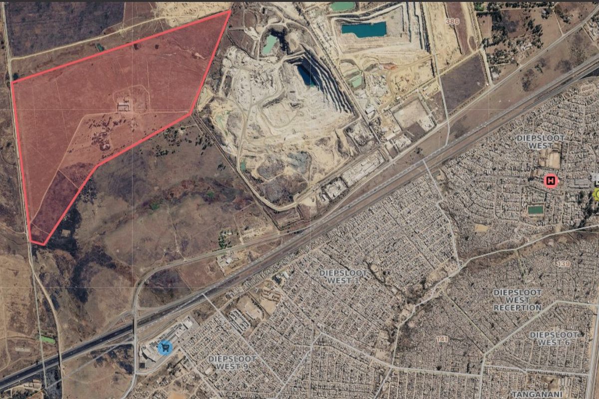 Aerial view of a large, undeveloped residential land parcel highlighted in red, situated near existing urban infrastructure and major transport routes.