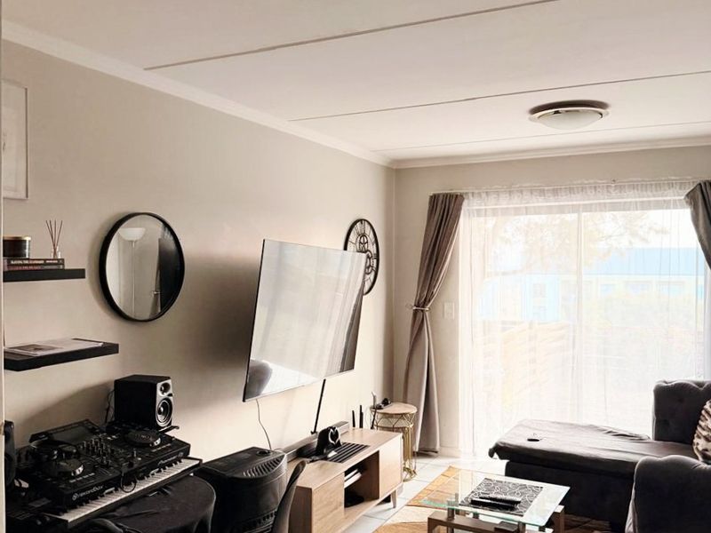 A living room featuring tiled flooring, floating wall shelves, and a sliding glass door providing natural light.