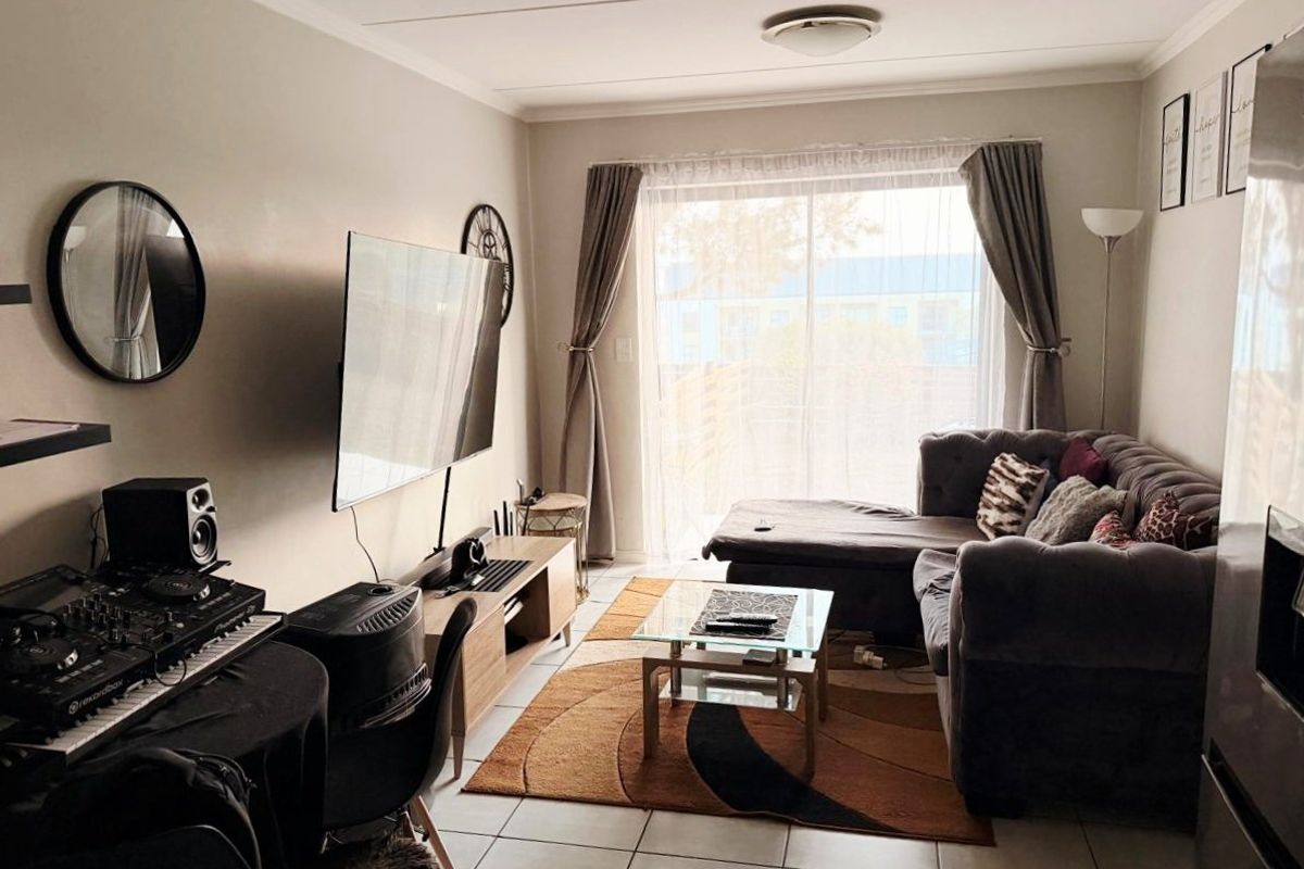 A comfortable living room featuring tiled flooring and a large sliding glass door that provides natural light and access to the outdoor area.
