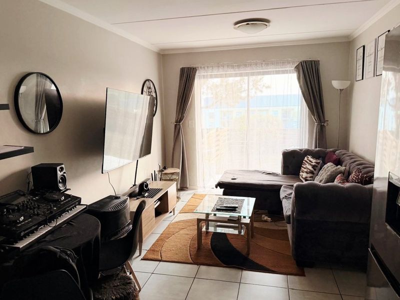 A comfortable living room featuring tiled flooring and a large sliding glass door that provides natural light and access to the outdoor area.