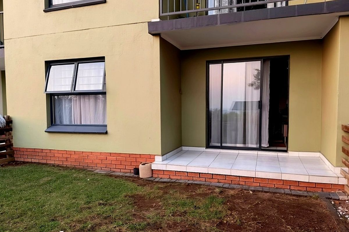 Ground floor apartment exterior featuring a tiled patio, sliding glass door access, and a small private garden area.