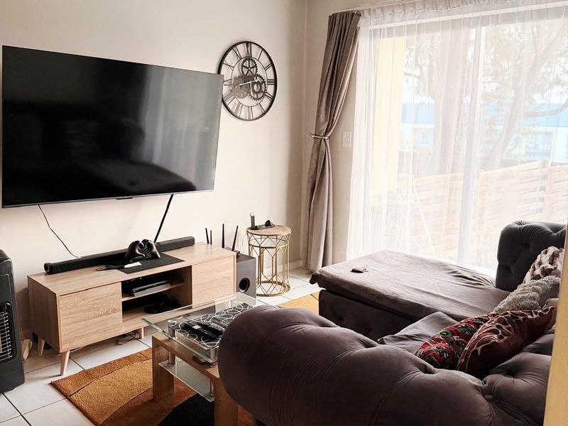 A well-maintained living room featuring tiled flooring and a large sliding glass door that provides natural light and access to the outdoor area.