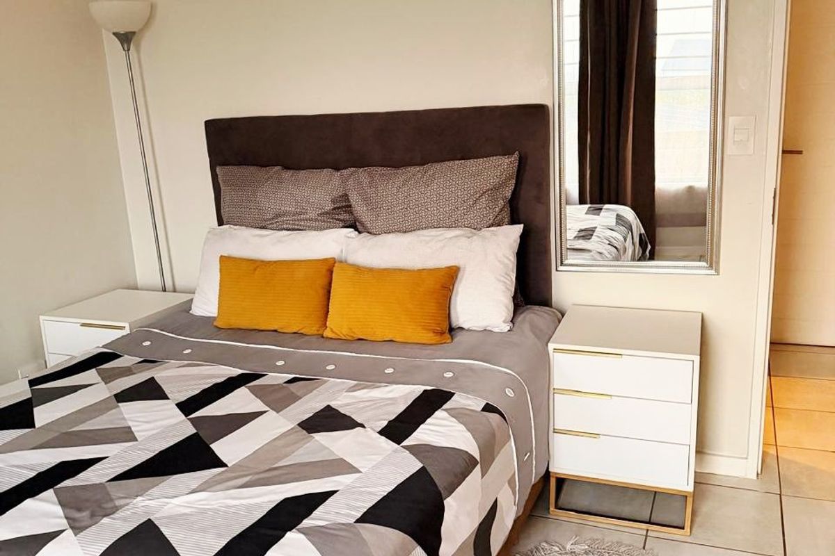 A well-maintained bedroom featuring neutral wall tones and clean tiled flooring, providing a comfortable and functional living space.