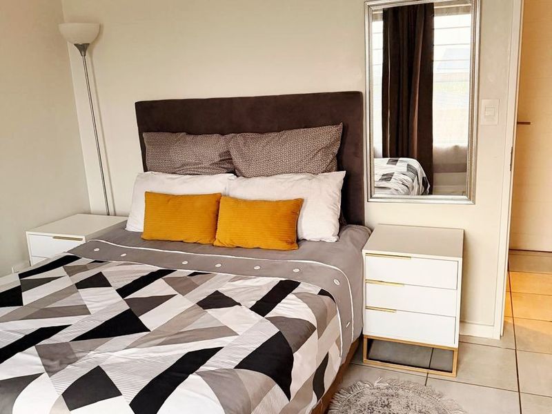 A well-maintained bedroom featuring neutral wall tones and clean tiled flooring, providing a comfortable and functional living space.