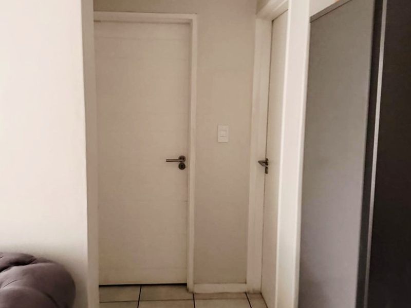 A functional hallway featuring tiled flooring and access to two internal rooms.