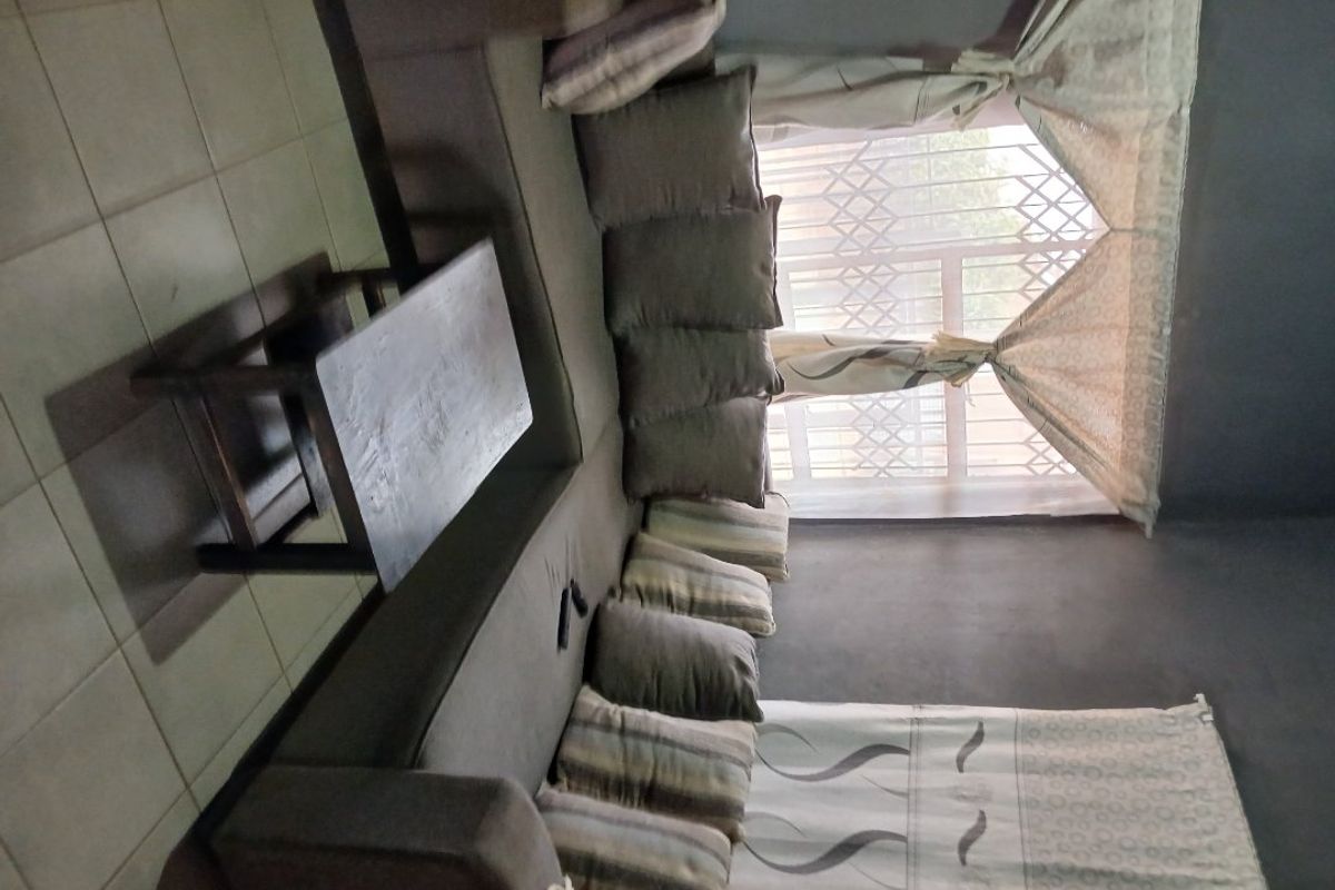 A living room area featuring tiled flooring and a window with security gate protection.