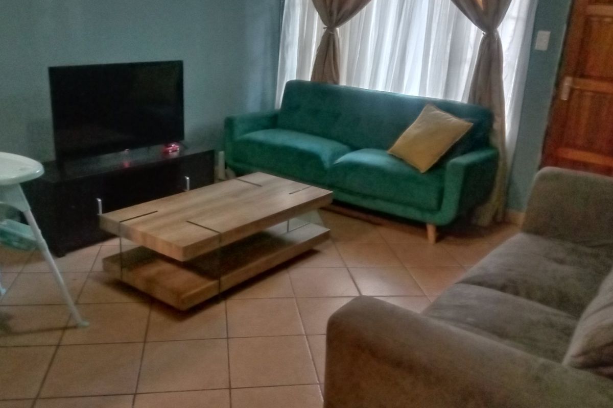 A living room area featuring tiled flooring and a wooden door, providing a functional space for relaxation.
