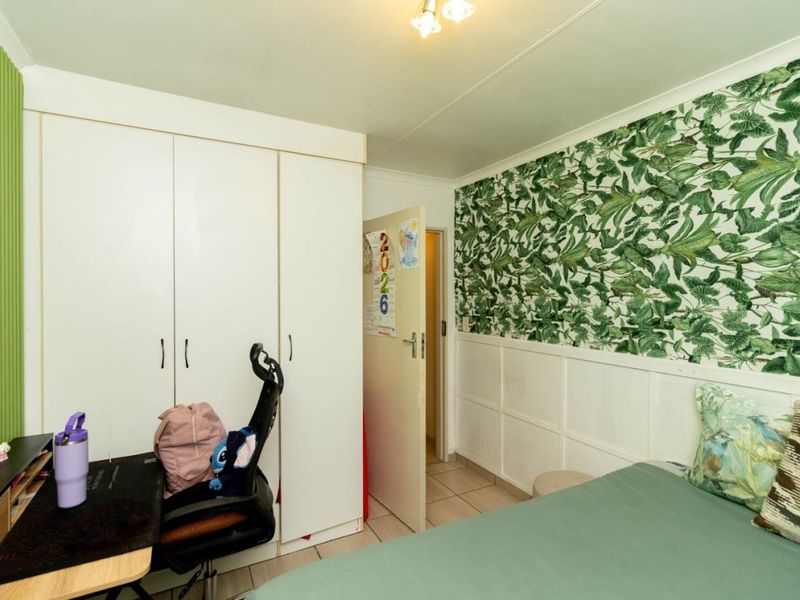 A bedroom featuring built-in wardrobes, tiled flooring, and decorative wainscoting with botanical wallpaper.