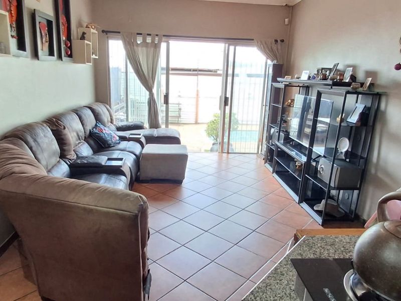 Open-plan living area featuring tiled flooring and large sliding glass doors that provide direct access to the outdoor patio and pool area.