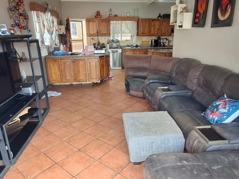 Open plan living area featuring tiled flooring and a functional kitchen with wooden cabinetry, providing a combined space for cooking and relaxation.