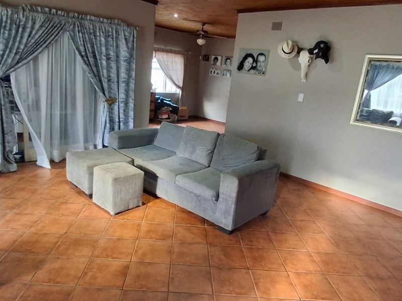 Spacious living room featuring terracotta-style tiled flooring, a timber-paneled ceiling with a fan, and large sliding glass doors providing natural light.