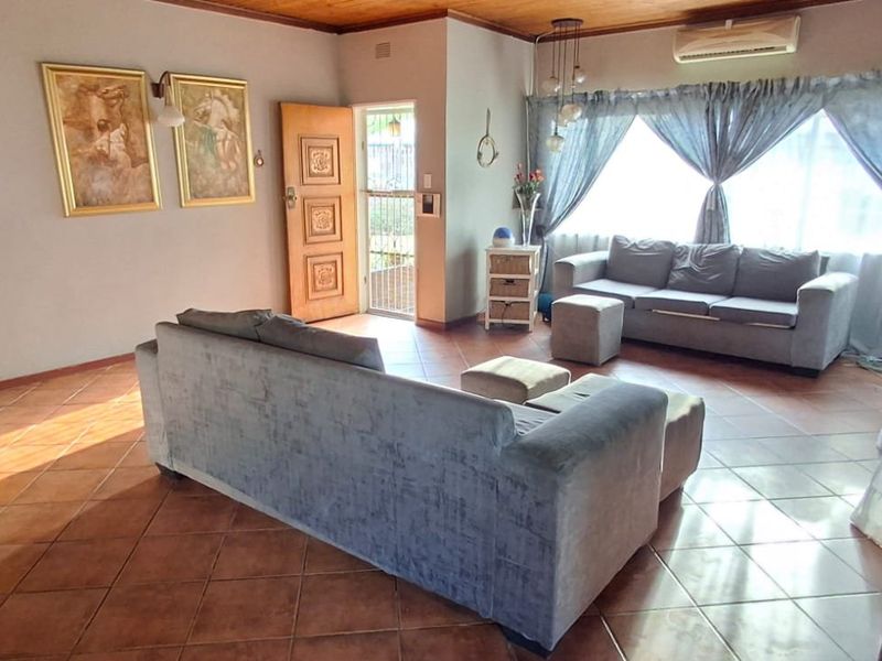 Spacious living room featuring terracotta floor tiles, a timber ceiling, and a wall-mounted air conditioning unit, providing a comfortable and functional living space.