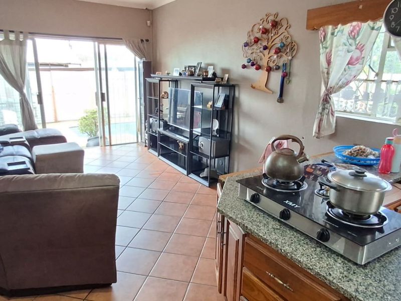 Open-plan living area featuring tiled floors, granite kitchen countertops, and sliding glass doors leading to an outdoor patio area.