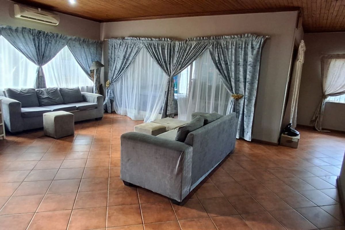Spacious living room featuring ceramic floor tiles, a timber-clad ceiling, and a wall-mounted air conditioning unit.