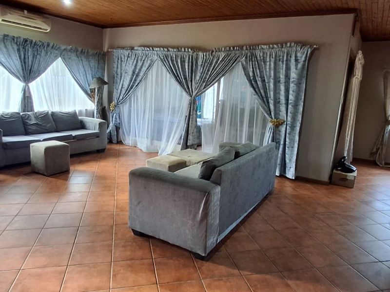 Spacious living room featuring ceramic floor tiles, a timber-clad ceiling, and a wall-mounted air conditioning unit.