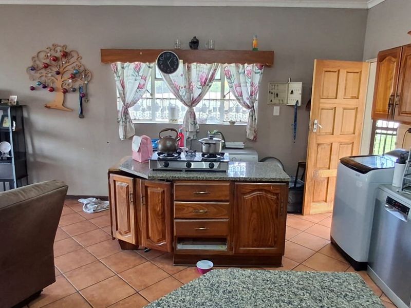 Open-plan living and kitchen area featuring granite countertops, wooden cabinetry, a gas hob, and tiled flooring throughout.