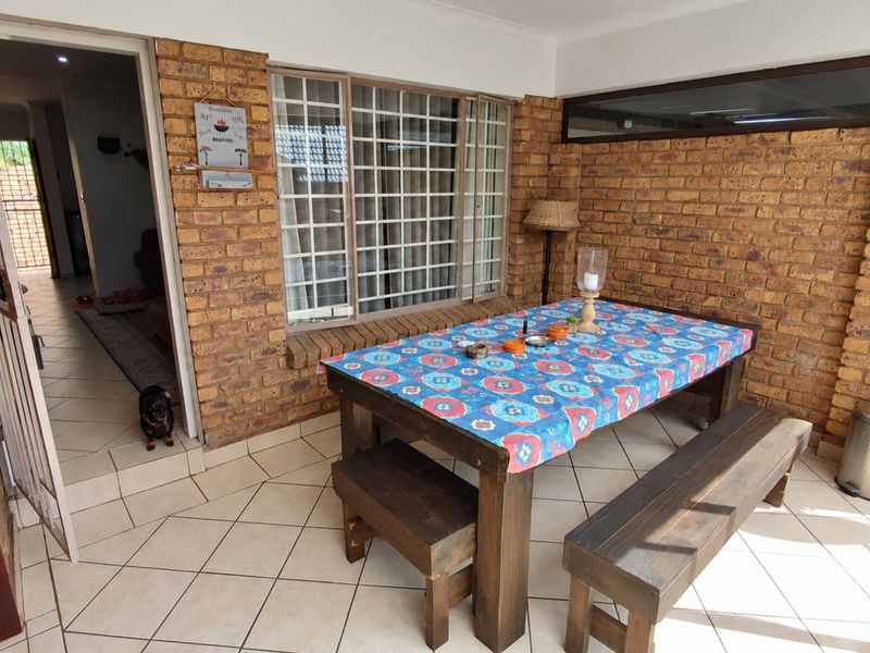 A covered patio area featuring exposed brick walls and tiled flooring, providing a functional outdoor space accessible from the main interior living area.
