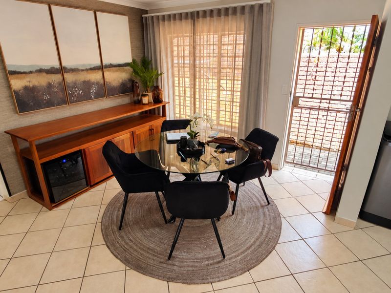 A bright dining area featuring tiled flooring, a sliding glass door with access to the exterior, and a secure metal gate.