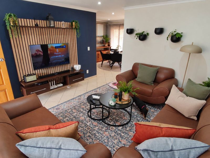 A well-maintained living room featuring a modern timber slat feature wall, tiled flooring, and recessed downlighting, creating a warm and inviting atmosphere.