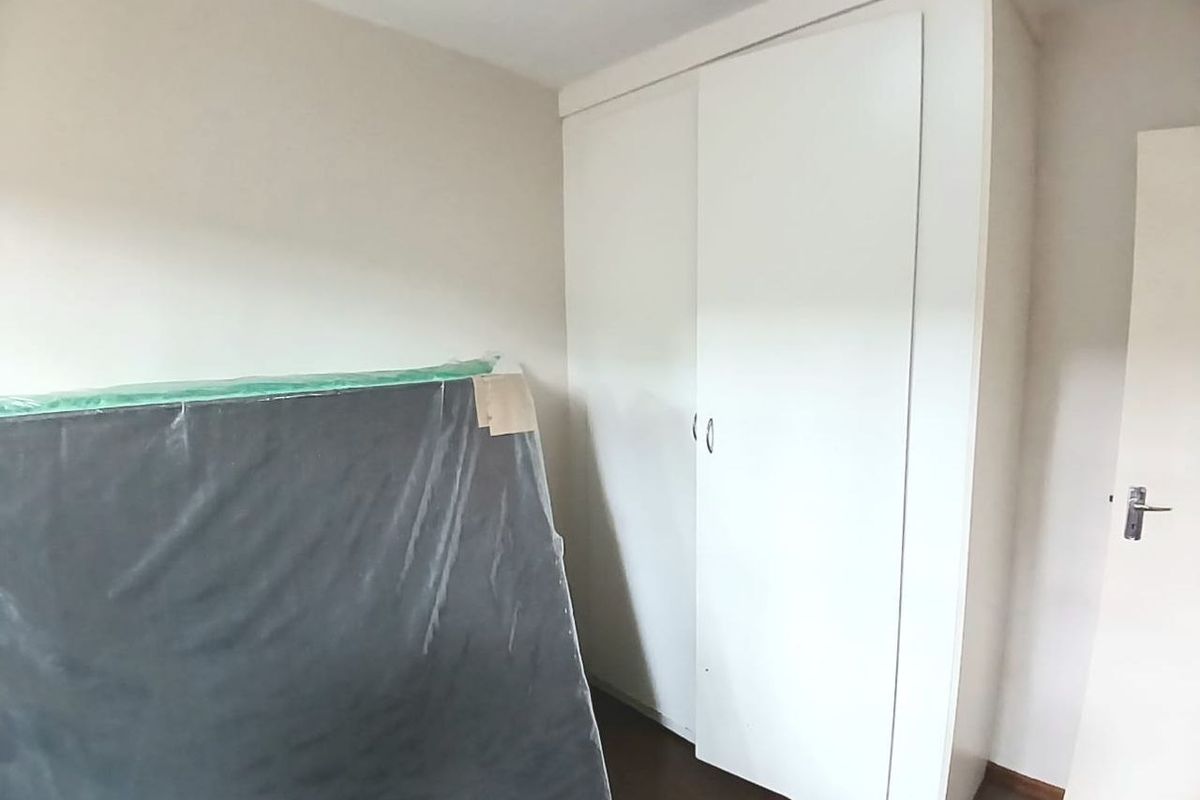 A simple bedroom featuring a white built-in wardrobe with sliding doors, providing practical storage space.