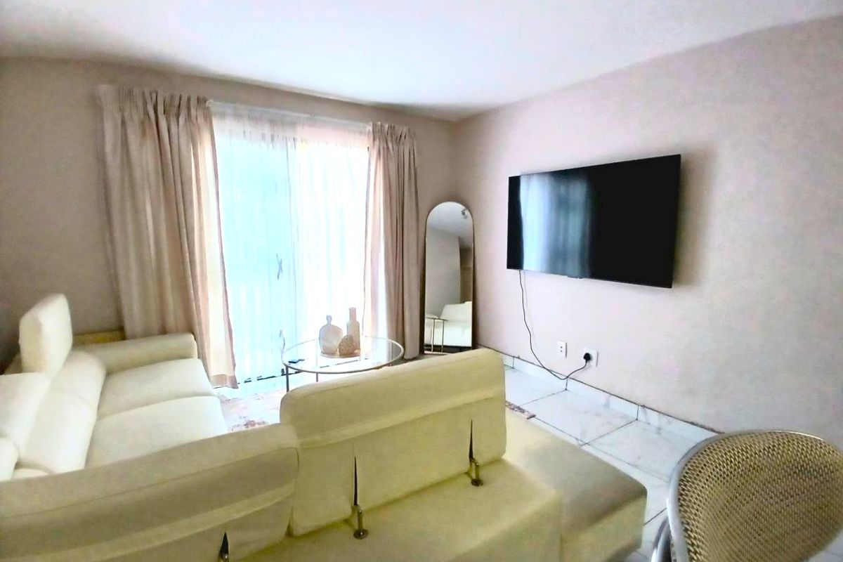 A bright living room featuring tiled flooring and a sliding glass door providing natural light.