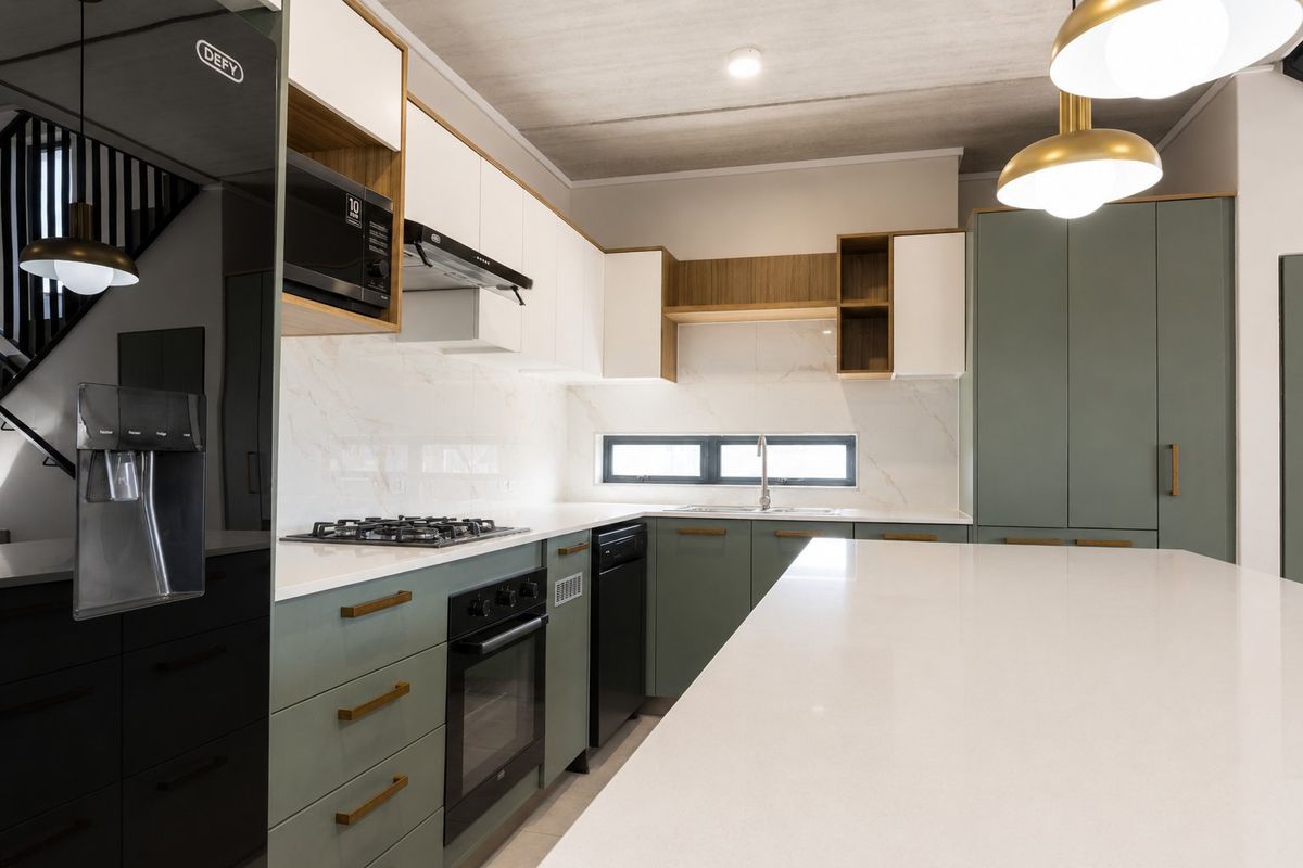 Modern kitchen featuring high-end cabinetry, stone countertops, integrated appliances, and a central island, finished with contemporary lighting and clean architectural lines.