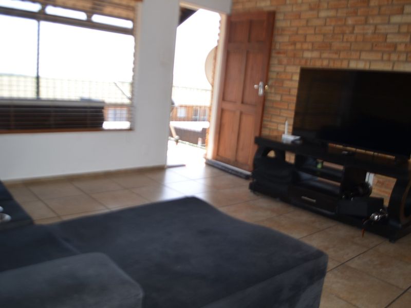 Living room featuring exposed brick wall, tiled flooring, and direct access to an outdoor area through a wooden door.