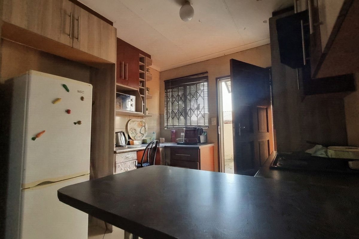A compact kitchen featuring built-in cabinetry, laminate countertops, and direct access to the exterior via a security door.