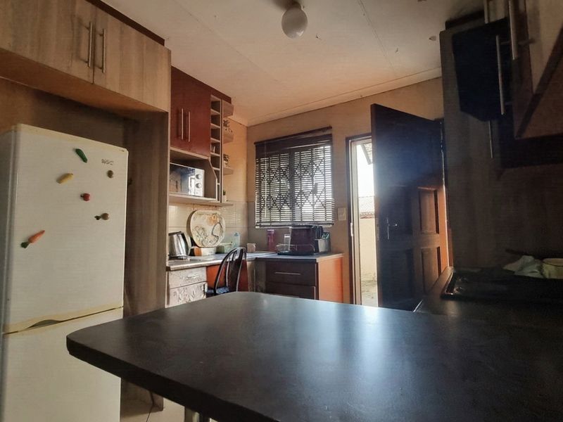 A compact kitchen featuring built-in cabinetry, laminate countertops, and direct access to the exterior via a security door.