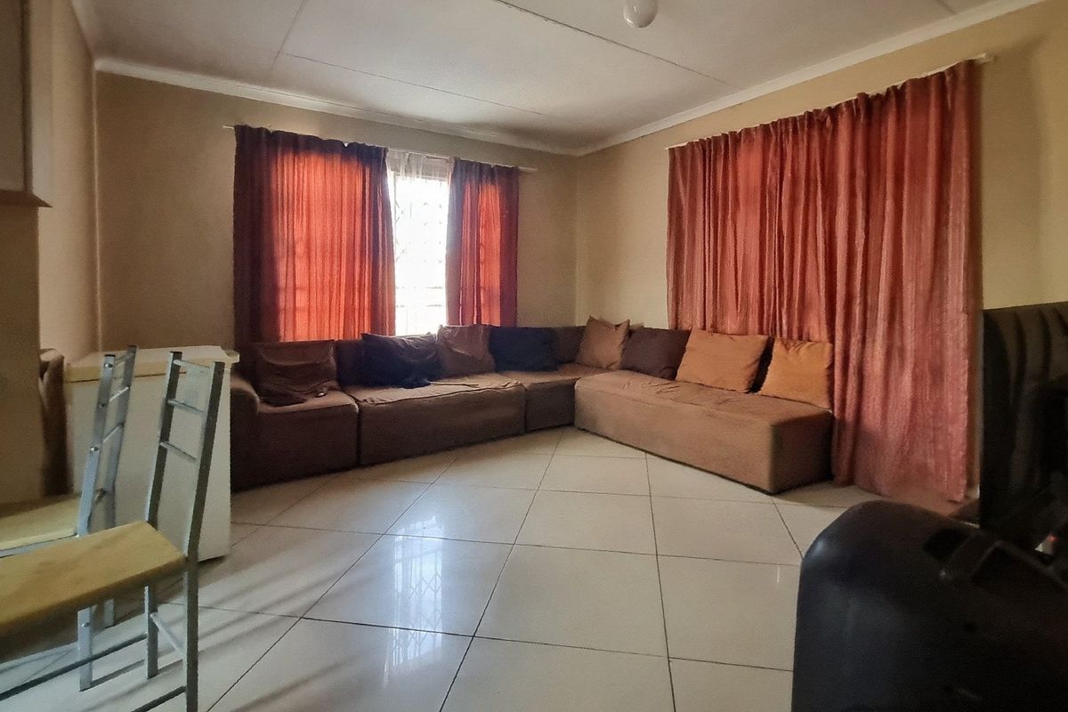 A spacious living room featuring neutral wall tones and large format floor tiles, providing a functional and comfortable base for interior design updates.