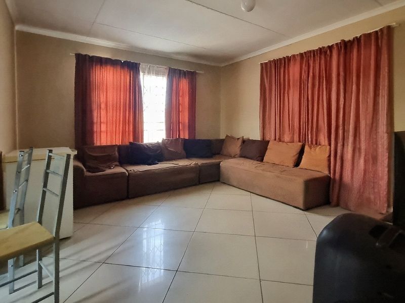 A spacious living room featuring neutral wall tones and large format floor tiles, providing a functional and comfortable base for interior design updates.