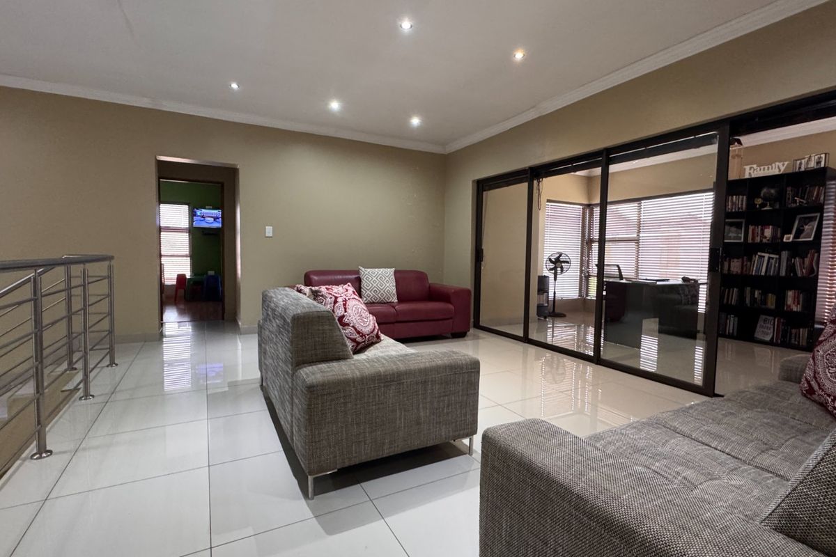 Spacious living area featuring polished tiled floors, recessed downlighting, and large sliding glass doors that provide access to an adjacent room.