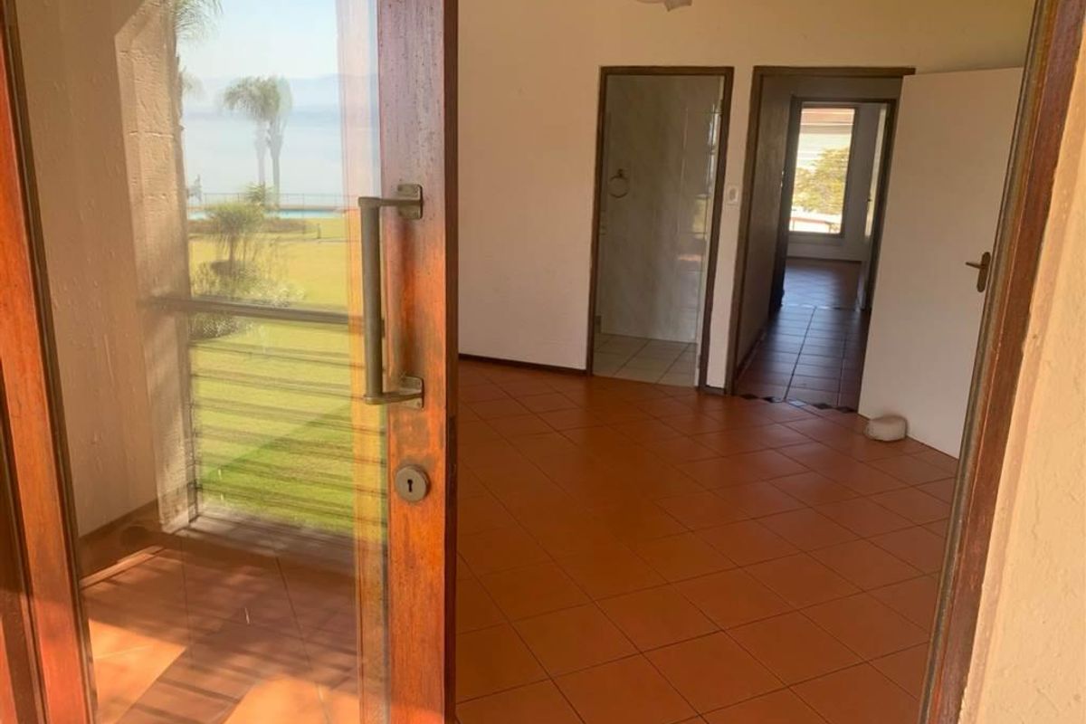 An empty living area featuring tiled flooring, a ceiling fan, and a sliding glass door providing access to an outdoor space.