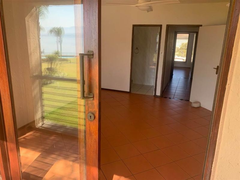 An empty living area featuring tiled flooring, a ceiling fan, and a sliding glass door providing access to an outdoor space.