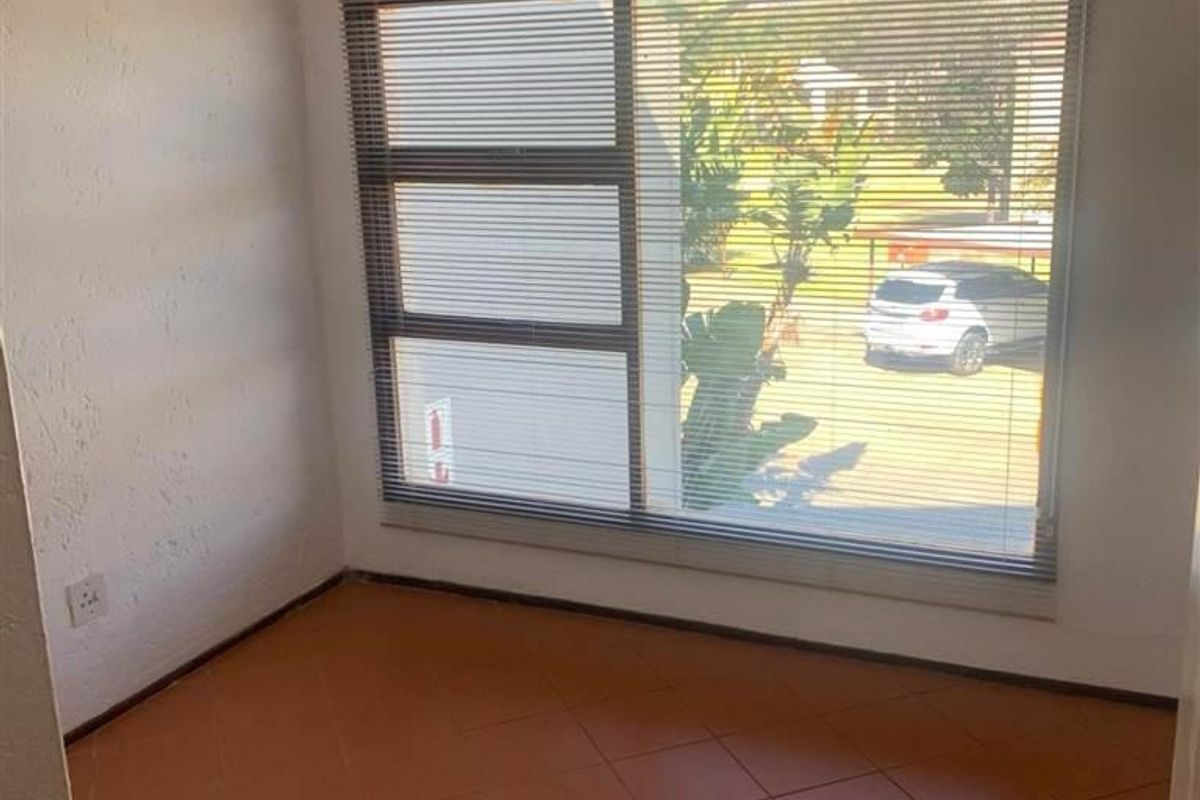 An empty bedroom featuring tiled flooring, a ceiling fan, and large windows with venetian blinds, offering a blank canvas for potential updates.