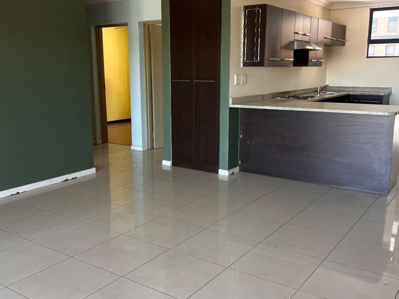 Open plan living and kitchen area featuring tiled floors, dark wood cabinetry, a breakfast bar, and neutral wall tones.