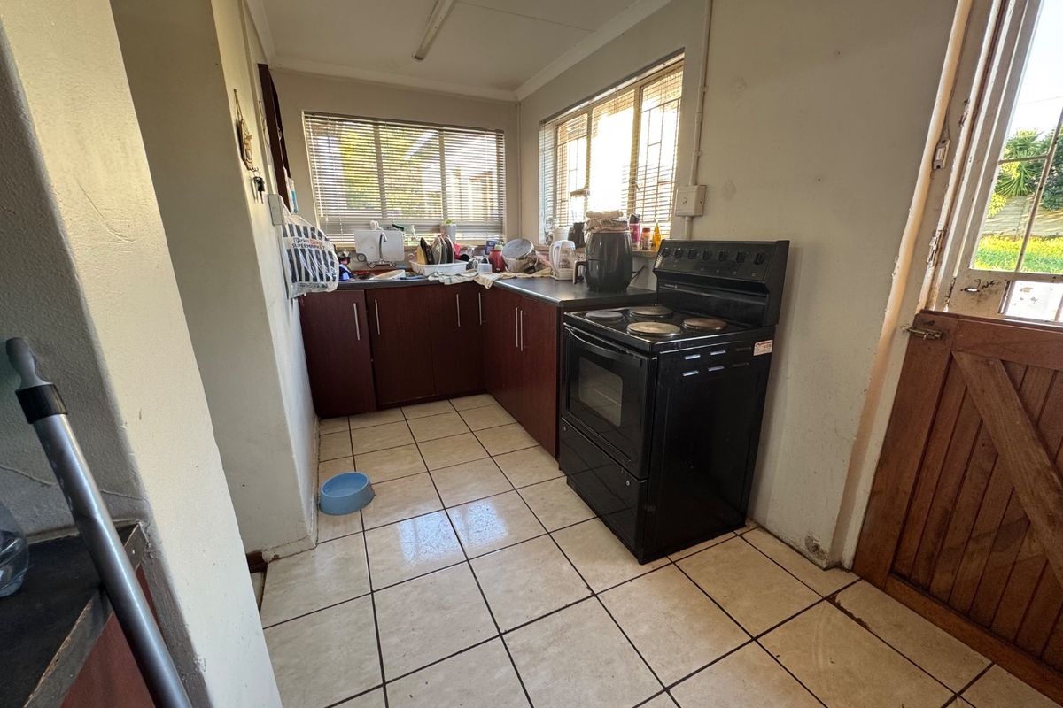 A functional kitchen featuring dark wood cabinetry, tiled flooring, and a freestanding stove, with direct access to the exterior via a stable door.