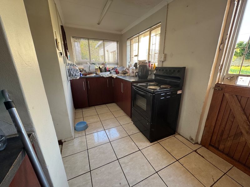 A functional kitchen featuring dark wood cabinetry, tiled flooring, and a freestanding stove, with direct access to the exterior via a stable door.