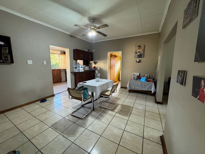 Open plan living and dining area featuring tiled flooring, a ceiling fan, and access to a secondary kitchen or utility space.