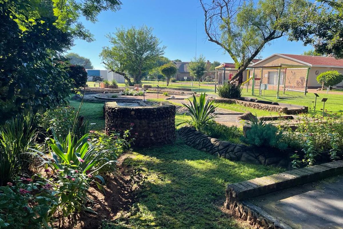 A well-maintained garden area featuring stone-clad landscaping, a decorative well, and established greenery, providing a pleasant outdoor recreational space.
