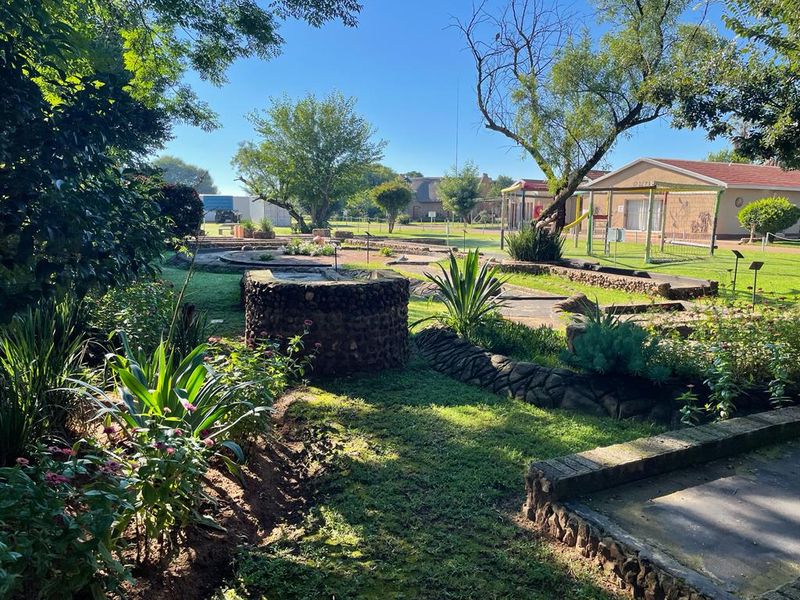 A well-maintained garden area featuring stone-clad landscaping, a decorative well, and established greenery, providing a pleasant outdoor recreational space.