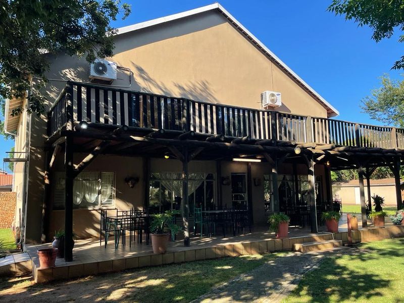 Rear view of the house featuring a spacious tiled patio, a wooden balcony above, and installed air conditioning units.