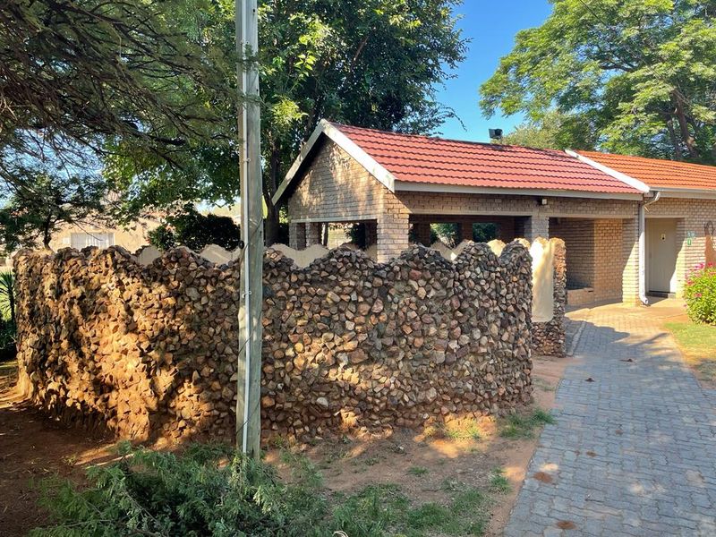 A view of the rear exterior featuring a decorative stone-clad wall, brick structure with a tiled roof, and a paved walkway.