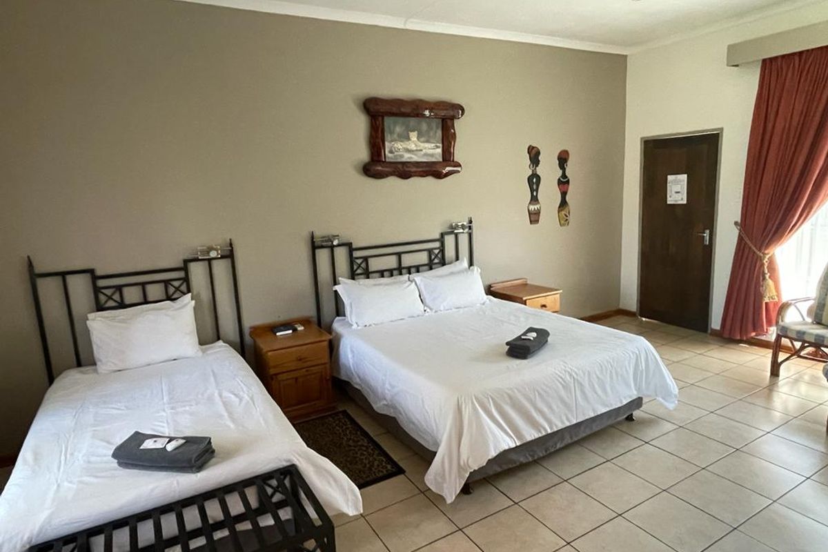 A spacious bedroom featuring neutral wall tones and durable tiled flooring, providing a functional and comfortable sleeping area.