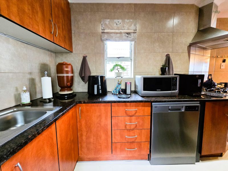 A functional kitchen featuring warm-toned laminate cabinetry, granite countertops, a tiled backsplash, and integrated stainless steel appliances.