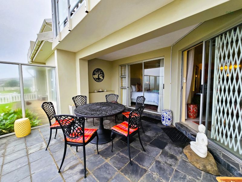 A covered outdoor patio featuring slate tile flooring and direct access to the interior through sliding glass doors with security gates.