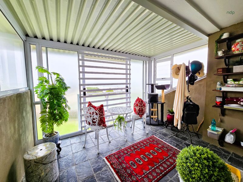 A covered patio area featuring slate tile flooring, corrugated metal ceiling, and sliding glass doors, providing a versatile outdoor living space.